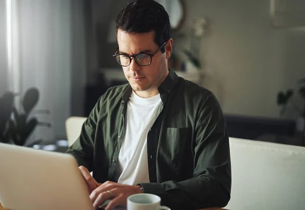 Людина серйозно працює на ноутбуці вдома — стокове фото