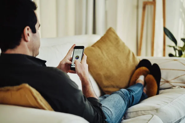 Чоловік зручно сидить на дивані за допомогою мобільного телефону — стокове фото