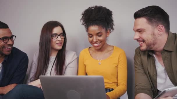 Un grupo de jóvenes estudiantes estadounidenses sentados en la universidad trabajando en un ordenador portátil juntos como un equipo — Vídeo de stock