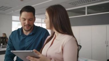Dijital tablet kullanan genç iş kadını ve işadamı modern ofiste yeni proje hakkında tartışmak