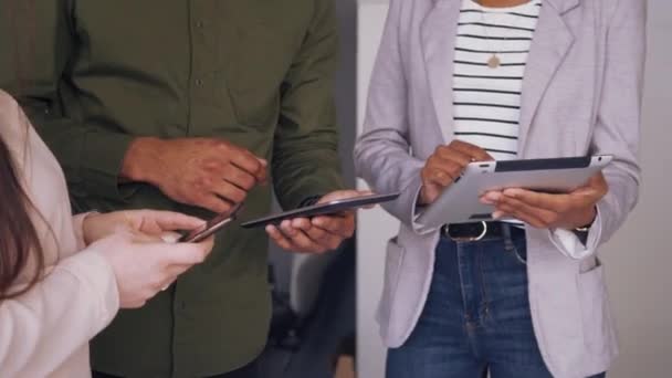 Крупним планом руки групи з трьох молодих бізнесменів, що стоять разом обговорюючи творчу ідею, використовуючи смартфон і цифрові планшети в офісі — стокове відео
