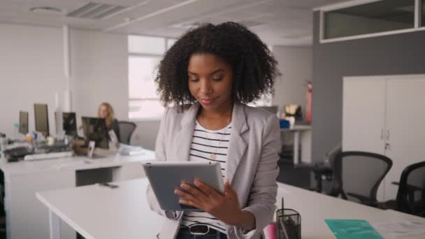 Sebevědomé mladé africké obchodženské používající digitální tablet před kolegy, kteří pracují na pracovišti v kanceláři na pozadí — Stock video