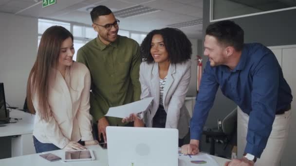 Groupe de jeunes entrepreneurs multiraciaux prospères occupés à discuter du rapport financier sur le lieu de travail lors d'une réunion dans un bureau moderne 