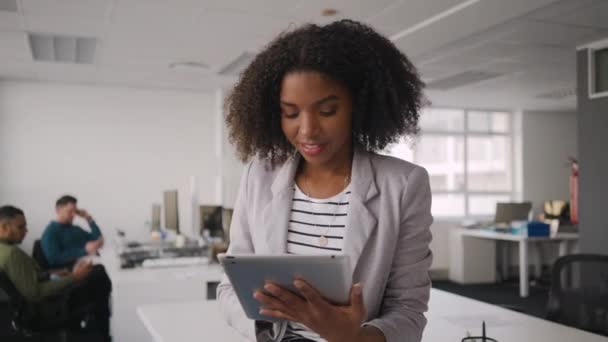 Retrato de sorridente pensativo bem sucedido jovem empresária usando tablet computador e sua equipe trabalhando na mesa no escritório — Vídeo de Stock