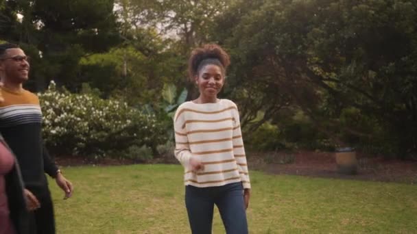 Gülümseyen Afrikalı genç kadın ellerini istiflemek ve parkta onları yükseltmek için arkadaşlarını çağırıyor — Stok video