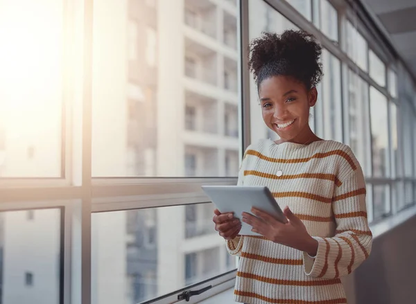 Confiante sorridente jovem empresária em desgaste casual com tablet digital olhando para a câmera de pé perto da janela do escritório — Fotografia de Stock