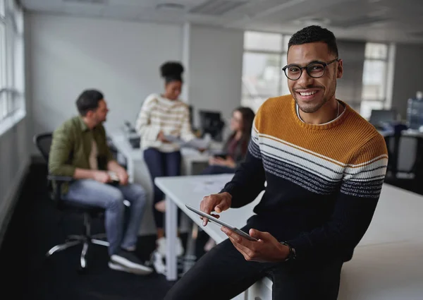 Портрет успішного усміхненого бізнесмена, який тримає цифровий планшет, дивлячись на камеру, що сидить перед командою в сучасному офісі — стокове фото