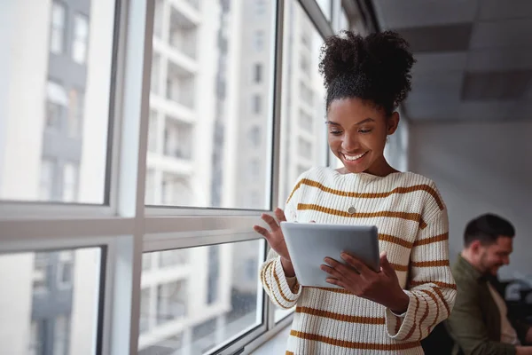 Mujer ejecutiva brasileña sonriente usando una tableta digital en un entorno arquitectónico moderno ambientado en América del Sur — Foto de Stock