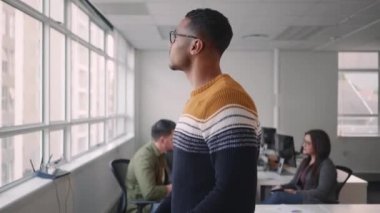 Gülümseyen kendinden emin genç işadamı iş timi önünde kollarından geçerken ofiste sohbet ediyor