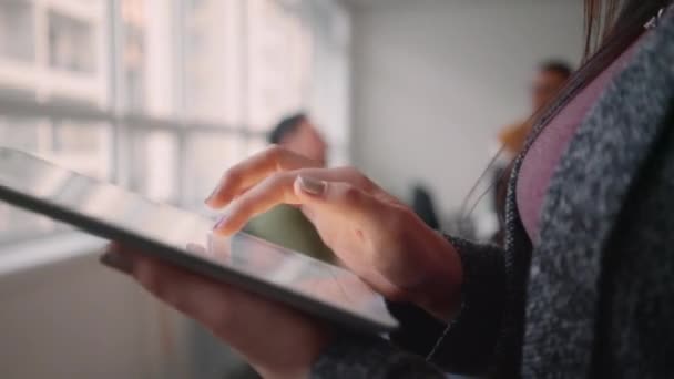 Primer plano de una empresaria en la oficina usando tableta digital de pie frente a un colega conversando en la oficina — Vídeos de Stock