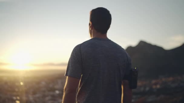 Feliz atleta masculino con auriculares celebrando el éxito y gritando en voz alta en la cima de la montaña al amanecer - hombre gritando de alegría — Vídeo de stock