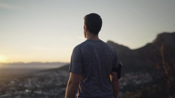Dolly lövés egy fiatal futó ember állt a hegy tetején élvezi a napfelkeltét-inspiráló — Stock videók