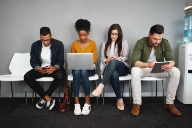 İşe alım sürecine hazırlanan modern araçları kullanarak iş görüşmesi için ofiste kuyrukta oturan çeşitli iş adayları