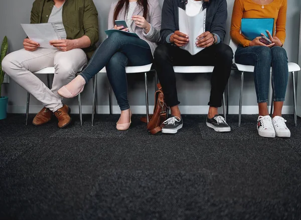 Sezione bassa di candidati al lavoro in attesa nel corridoio di preparazione per il processo di reclutamento - foto di piedi diversi seduti in fila in attesa di un colloquio di lavoro — Foto Stock