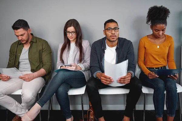 Grupo de jóvenes candidatos multirraciales a la espera de una entrevista sentados en silla con sus currículums — Foto de Stock