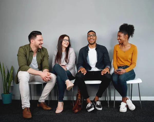 Diverso grupo de amigos sentados en silla esperando en la cola sonriendo y disfrutando juntos - grupo joven de amigos experimentando un sentido de pertenencia e inclusión y conexión — Foto de Stock