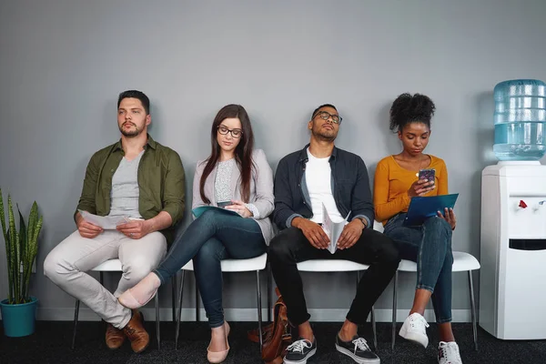 Diverso aburrido joven solicitante sentado en la silla en fila en la sala de espera para la entrevista de trabajo en la oficina - grupo joven de personas auténticas reales — Foto de Stock