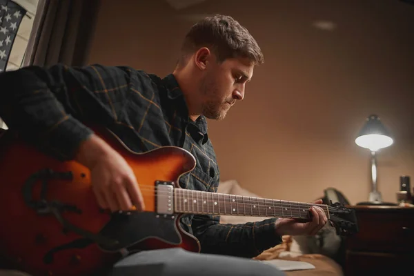 Zbliżenie młodego mężczyzny doświadczonego artysty grającego na gitarze w swoim mieszkaniu — Zdjęcie stockowe