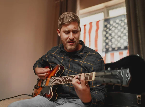 Bello americano che suona la chitarra acustica e canta con passione a casa — Foto Stock