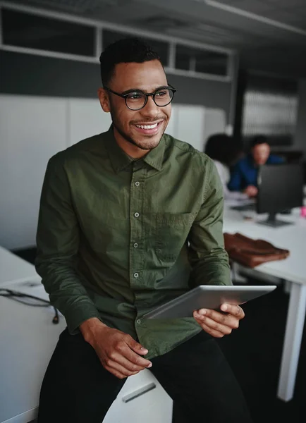 Pensativo sorridente jovem empresário segurando tablet digital olhando para longe enquanto sentado em seu local de trabalho no escritório — Fotografia de Stock