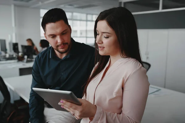 Glimlachende zakenvrouw toont online data of presentatie op digitale tablet aan zijn mannelijke collega — Stockfoto