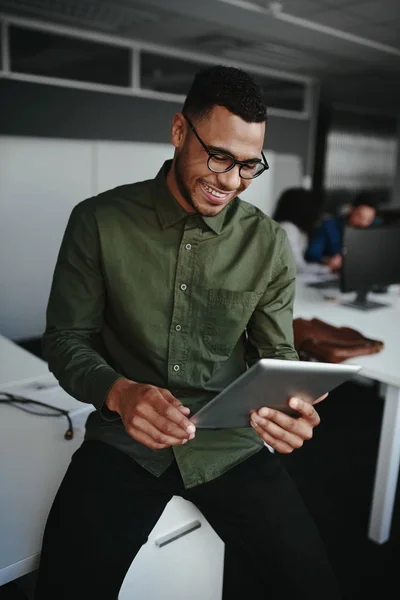 Sonriente joven hombre de negocios que trabaja en línea en la tableta digital mientras está sentado en el escritorio en una oficina — Foto de Stock