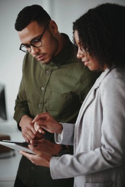 Genç Afrikalı Amerikalı iş adamı ve iş kadını ofisindeki dijital tablet bilgisayarda projeyi tartışıyor