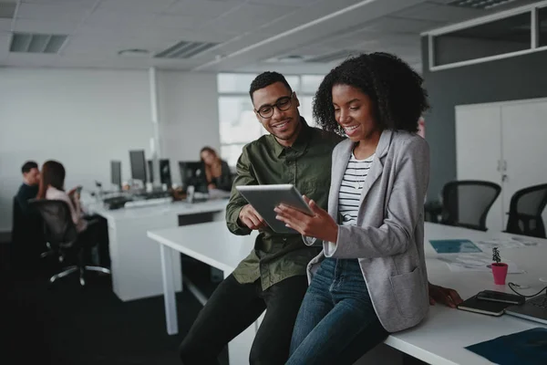 Exitosos dos jóvenes empresarios afroamericanos sentados en el escritorio usando tableta digital mientras su colega en segundo plano en la oficina — Foto de Stock