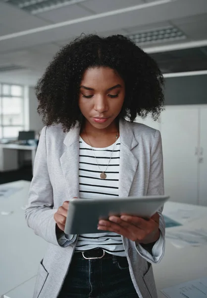 Uma atraente mulher de negócios afro-americana de pé na frente da mesa usando um tablet digital no escritório moderno — Fotografia de Stock
