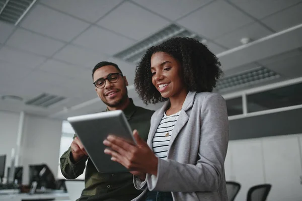 Portret van lachende professionele jonge Afro-Amerikaanse zakenvrouw toont gegevens op digitale tablet aan mannelijke collega in het kantoor — Stockfoto