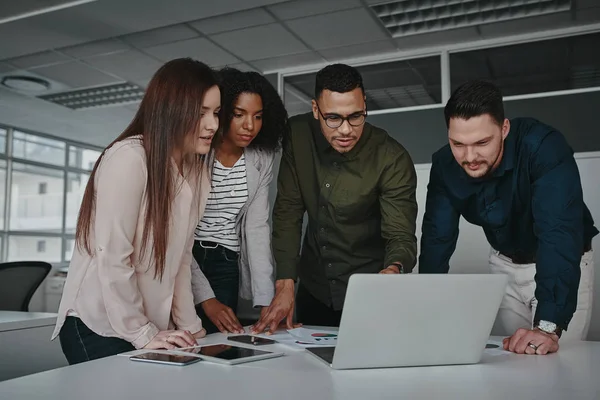 Grupo de jóvenes empresarios multiétnicos inteligentes discutiendo ideas mientras mira el ordenador portátil — Foto de Stock
