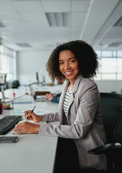 Retrato de uma jovem africana americana sorridente empresária com planejamento diário e computador na mesa olhando para câmera no escritório — Fotografia de Stock
