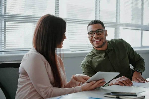 Jonge zakenman gebruikt een digitale tablet om informatie te bespreken met haar collega in een modern kantoor — Stockfoto