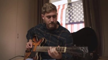 Gitar çalma pratiği yapan yaratıcı bir müzisyen. Kalemle deftere notalar yazıyor.