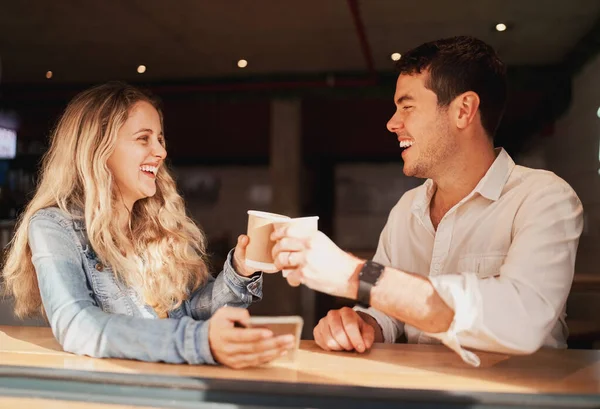 Smiling young friends in a coffee shop spending time together toasting with their disposable coffee cups — Stock Photo, Image