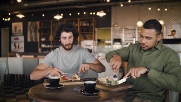 Jóvenes amigos multiétnicos disfrutando de un almuerzo italiano en la cafetería durante el descanso de la oficina mientras les gusta la comida — Vídeo de stock