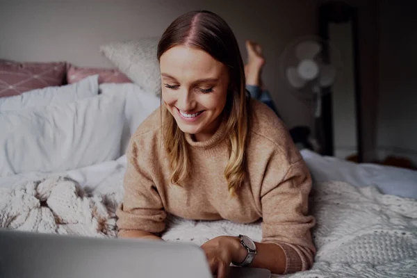 Portret van vrolijke jonge zakenvrouw werken op haar laptop in haar slaapkamer thuis - student leren online cursussen een — Stockfoto