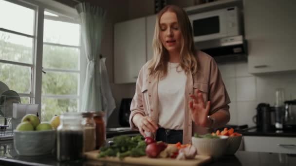 Sorrindo bela jovem blogueira mostrando ingredientes saudáveis frescos para cozinhar alimentos na cozinha durante o período de quarentena — Vídeo de Stock