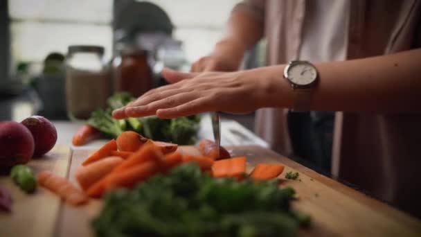 Close-up van een vrouw snijden wortel met keukenmes op snijplank en het bereiden van salade in de keuken — Stockvideo