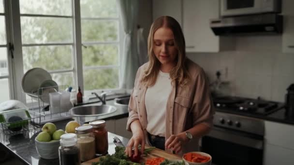 Jovem blogueira cozinhar comida saborosa e saudável na cozinha durante o confinamento em casa — Vídeo de Stock