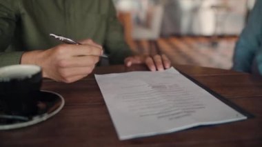 İş ortaklarının seçici odak noktası modern kafede kahve içerken el sıkışma sözleşmesi imzalaması