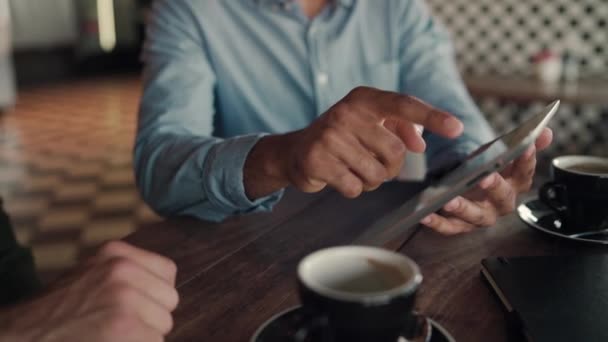 Enfoque selectivo de las manos del hombre de negocios mostrando productos y servicios al cliente bebiendo café en la cafetería — Vídeos de Stock