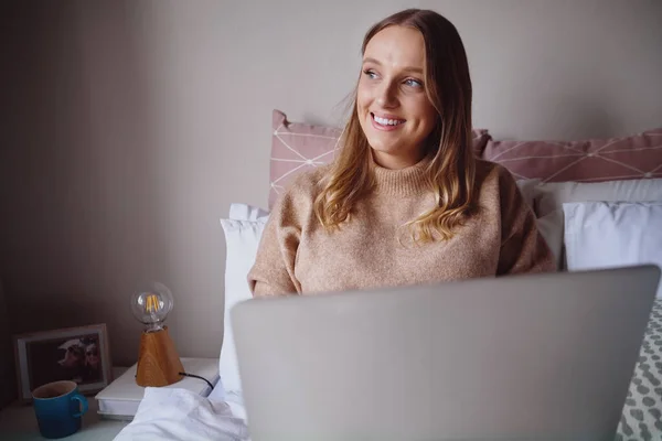 Bedachtzame jonge zakenvrouw werkt op laptop van thuis uit in haar slaapkamer - student leert nieuwe dingen online — Stockfoto