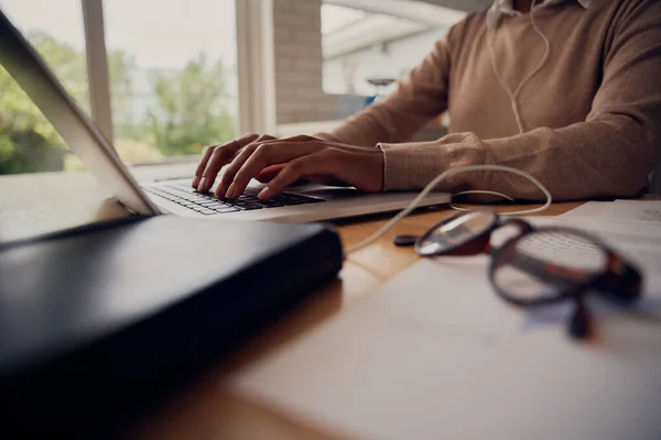 Primer plano de la mano femenina escribiendo en el teclado del ordenador portátil mientras está sentado en casa con documentos y anteojos — Foto de Stock