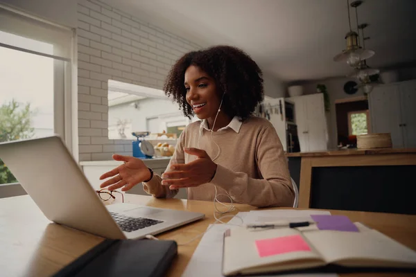イヤホンを使用しながらビデオ通話でオンライン会議を行う成功したアフリカのビジネス女性 — ストック写真