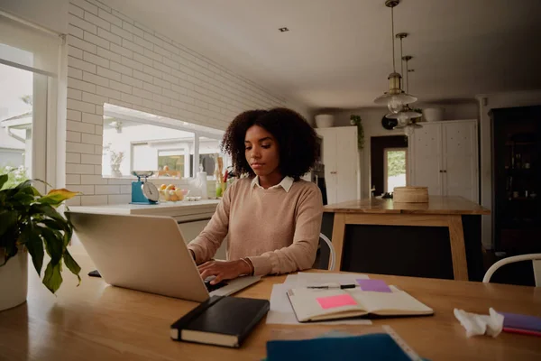 Vrouwelijke ondernemer thuis werkend op laptop met zakelijke documenten op tafel — Stockfoto