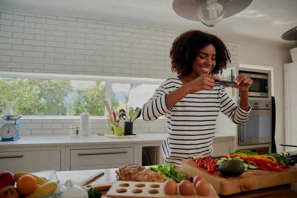 Side video of young successful female food blogger taking picture of freshly slices and chopped vegetables in modern kitchen — Stock Photo, Image
