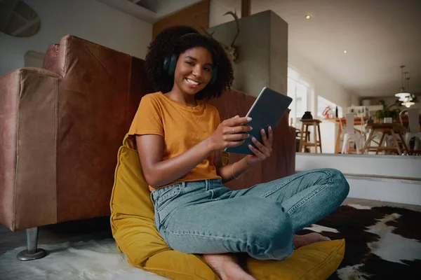 ワイヤレスヘッドフォン付きデジタルタブレットを使用して自宅でビデオを見て美しい若い女性の低角度の肖像画ビュー — ストック写真