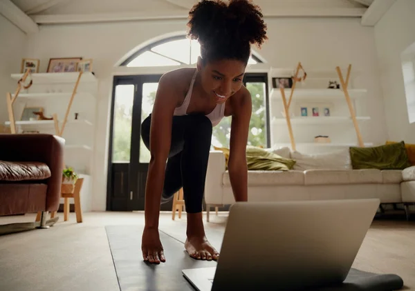 Крупним планом портрет щасливої жінки, що дивиться відео на ноутбук під час вправ на йога килимок вдома під час блокування коронавірусу — стокове фото