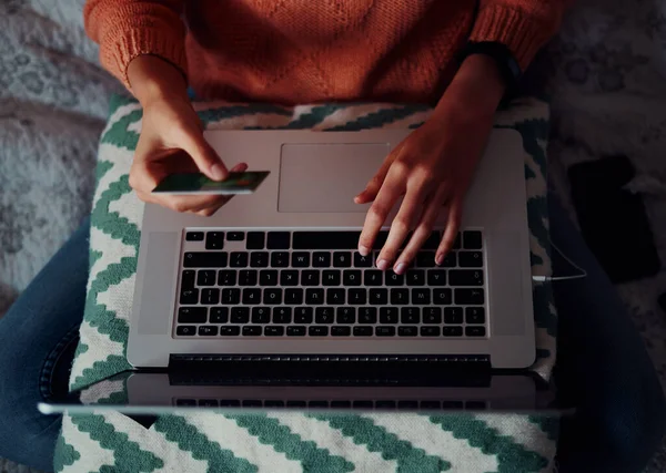 High-angle close-up zicht van jonge vrouw hand holding ban card voor het maken van online betaling met behulp van laptop thuis — Stockfoto
